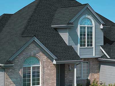 Close up of a mid-class home with black GAF shingles on its roof